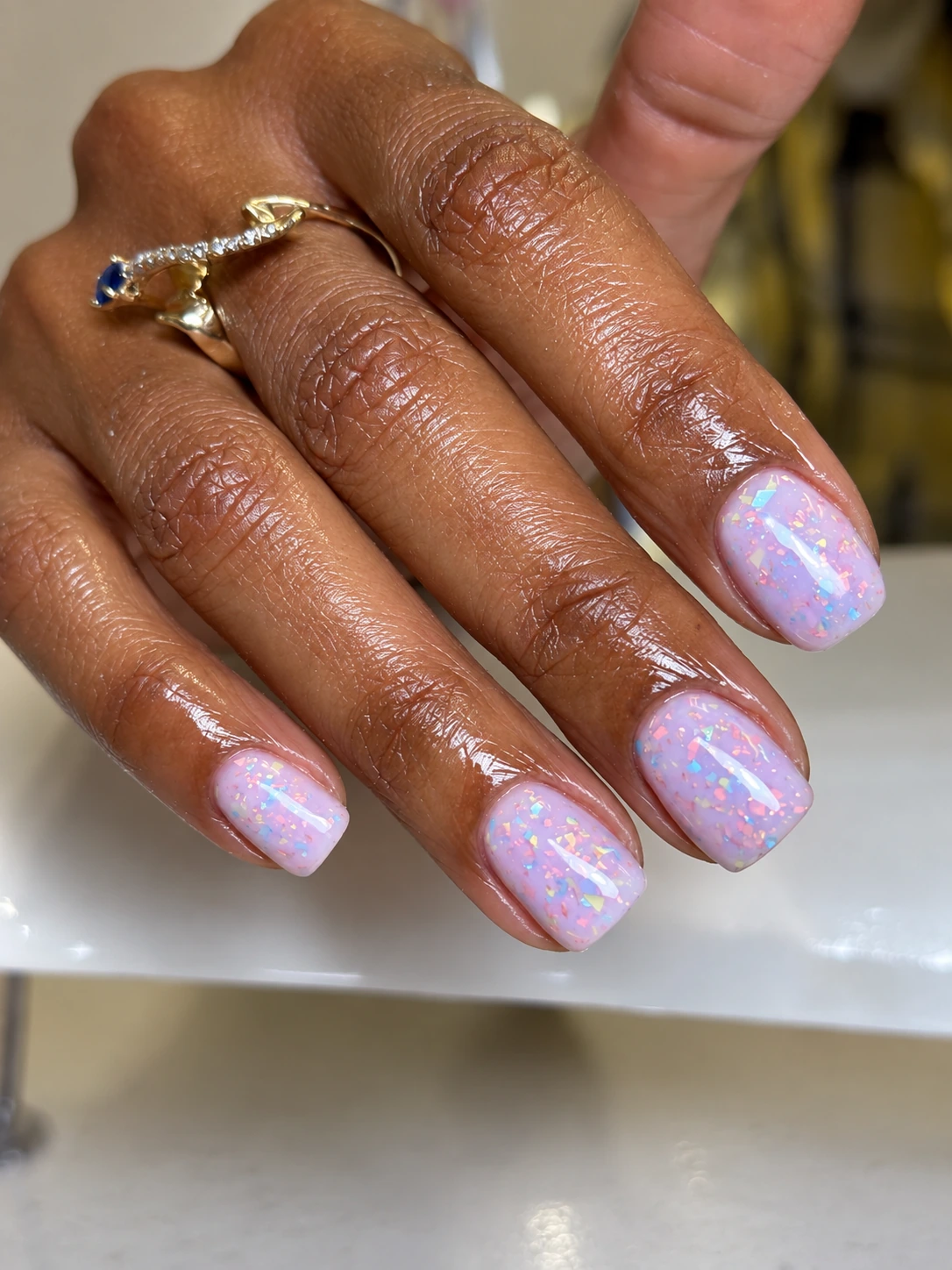 Lavender gel manicure with iridescent flakes on short, softly squared nails